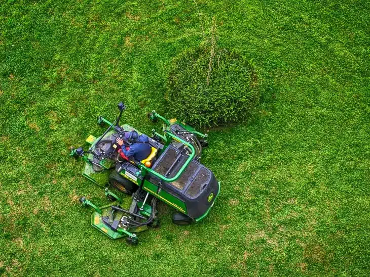 green and black ride on lawn mower on green grass field during daytime